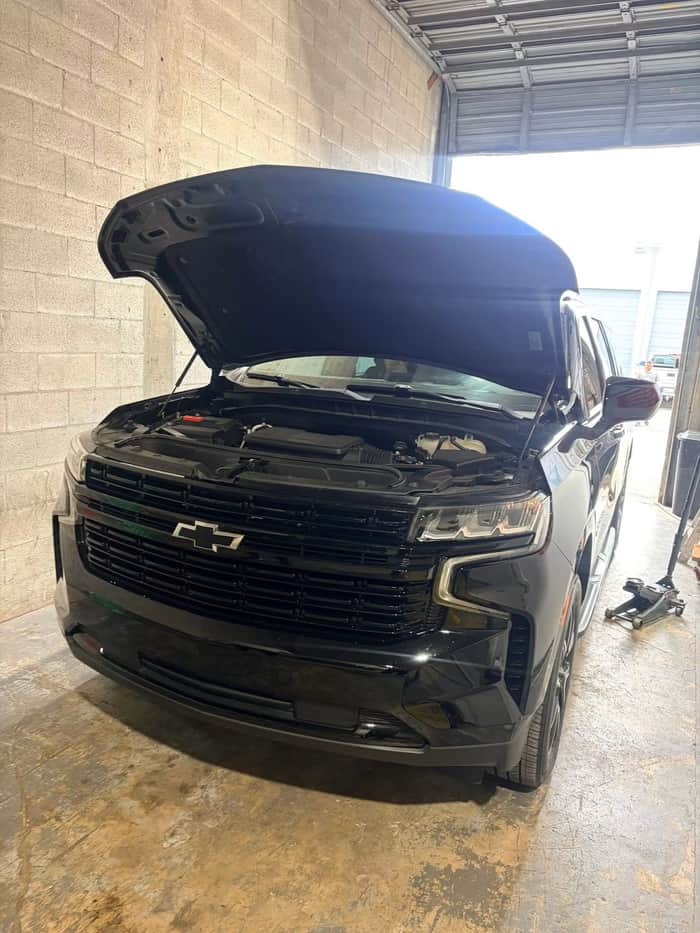 Black Chevrolet Tahoe with hood open in the shop