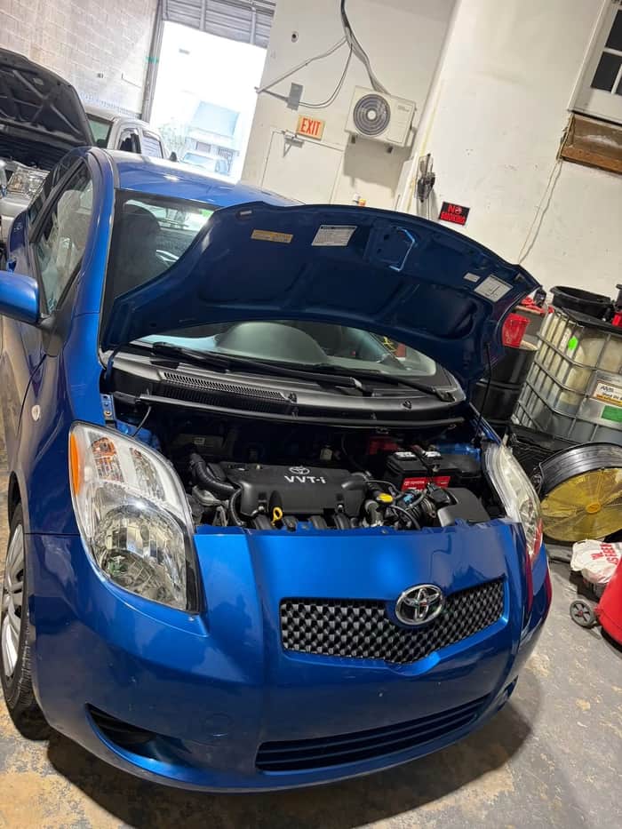 Blue Toyota Yaris with hood open in the shop