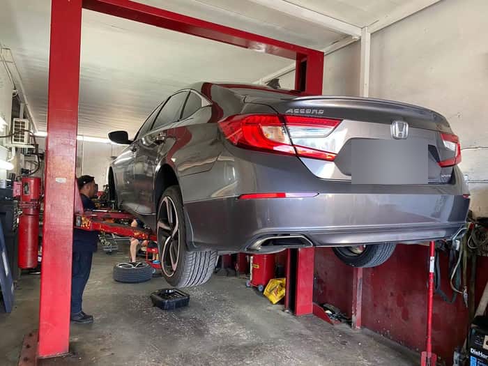 Gray Honda Accord raised on the lift with a wheel removed